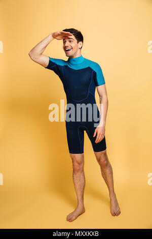 In voller Länge Porträt der glückliche junge Mann in Badeanzug weit über Gelb Hintergrund isoliert gekleidet Stockfoto