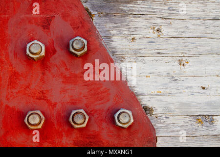 Rote Metall Platte mit großen Schraube schrauben fixiert zu einer Kreuzung in Holz- säule Girder im Haus Dach- und Dichtungsbahnen verwendet. Stockfoto