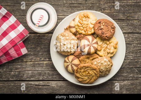 Verschiedene Arten von sweet Cookies auf Platte und die Milch in der Flasche. Stockfoto