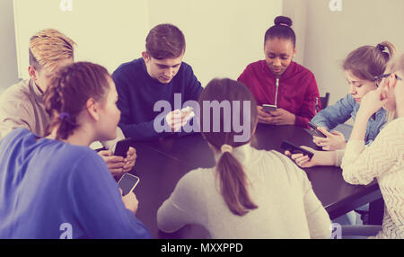 Junge Mitschüler über ihre Smartphones intensiv während der Klassen Stockfoto