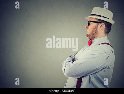 Seitenansicht eines chubby glücklicher Mann im eleganten Outfit mit Bow Tie und Strohhut Weg zuversichtlich Stockfoto