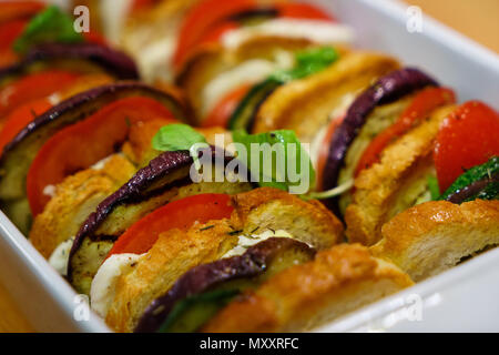 Flach, oben Ofen gebacken geschnittenes Gemüse (Tomaten, Auberginen und Zucchini) mit Mozzarella Käse und Baguette Scheiben mit Basilikum gekleidet. Stockfoto