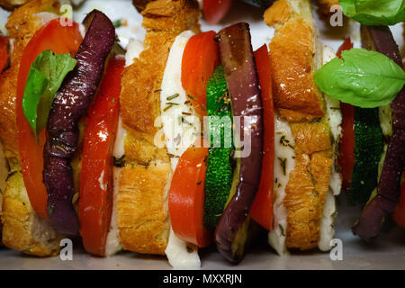 Flach, oben Ofen gebacken geschnittenes Gemüse (Tomaten, Auberginen und Zucchini) mit Mozzarella Käse und Baguette Scheiben mit Basilikum gekleidet. Stockfoto