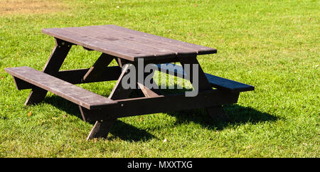 Leere schmutzig braun Picknicktisch auf grünem Gras im Sonnenlicht. Stockfoto