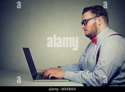 Seitenansicht der dicke Mann in formalen Outfit und Gläser mit Laptop bei der Arbeit in sitzender Lebensweise Stockfoto