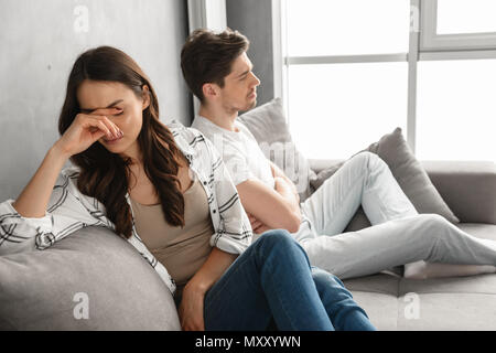 Foto von enttäuscht Paar sitzen zusammen auf dem Sofa zu Hause mit verärgert Aussehen und Ausdruck auf weißem Hintergrund Streit Stockfoto