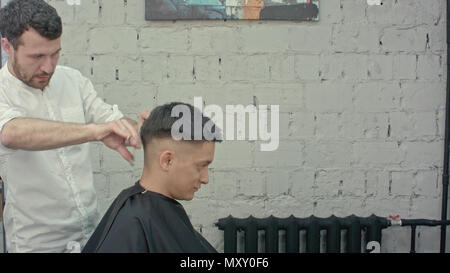 Tolle Zeit im barbershop. Fröhlicher junger bärtiger Mann, Haarschnitt, Friseur Stockfoto