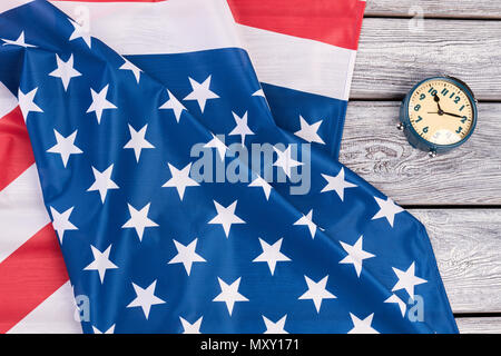 USA-Flagge und Mechanischer Wecker. Nationalflagge von Amerika und blau Wecker auf alten hölzernen Hintergrund. Zeit für patriotischen Stolz. Stockfoto