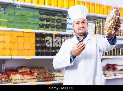 Happy shop Personal bietet Lebensmittel und gefüllten Regalen hinter Stockfoto