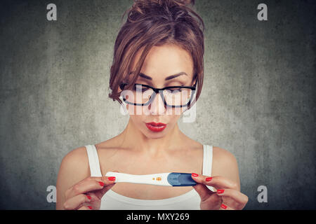 Junge Frau entsetzt die Augen nicht glauben, dass bei der Überprüfung der positiven Schwangerschaftstest Stockfoto