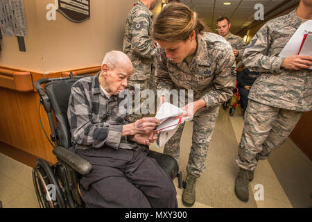 Master Sgt. Jamie Nieves, Mitte, Bauingenieur 177th Squadron, gibt Armee Weltkriegveteran Charles Crabiel der Karte während des 16. jährlichen Urlaub ongfest' an der New Jersey Veterans Memorial Home in Vineland, N. J., Dez. 13, 2016. Mehr als 80 Viertklässler aus der Seaview Volksschule in Linwood, N.J., und 18 Flieger sang holiday Songs und ausgeteilten Karten zu den Bewohnern des Hauses während der Veranstaltung. (U.S. Air National Guard Foto von Master Sgt. Mark C. Olsen/Freigegeben) Stockfoto