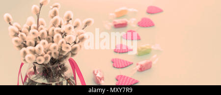 Festliches Arrangement in einem Glas Vase mit Zweigen palmkätzchen. Helle Candy Girlanden auf einem rosa Hintergrund. Stockfoto