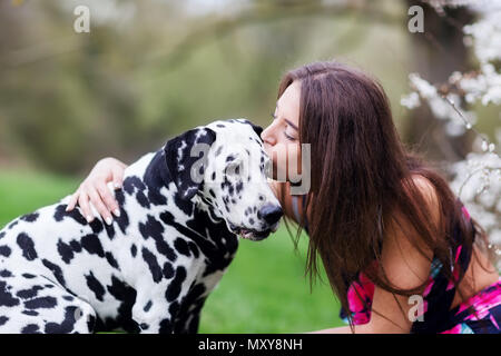 Bild einer jungen Frau, die ihren Dalmatiner Hund gibt einen Kuss Stockfoto