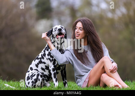 Porträt einer Frau sitzen zusammen mit einem Dalmatiner Hund auf der Wiese Stockfoto