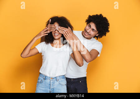 Portrait eines glücklichen jungen afro-amerikanische Mann für seine Freundinnen Augen isoliert auf gelbem Hintergrund Stockfoto