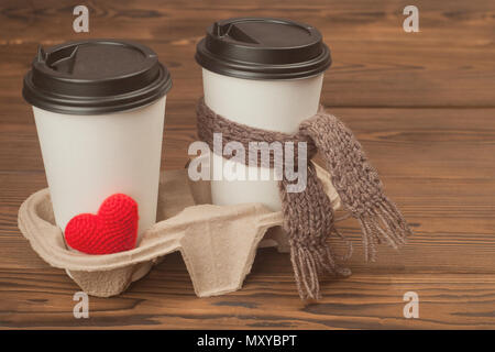 Zwei Tassen Kaffee mit Stricken sie Herz und Schal auf Holz- Hintergrund Stockfoto