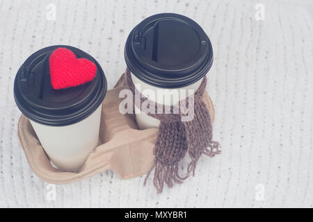 Zwei Einwegbecher für Getränke Kaffee oder Tee aus Karton, Halter, Stricken, Spielzeug, rote Herzen und braunen Schal, neues Jahr Konzept Stockfoto