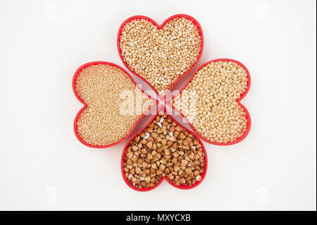 Herzen gefüllt mit Amaranth, Hirse und Quinoa Form ein Kleeblatt Muster isoliert auf weißem Stockfoto