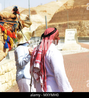 Ein tourist für ein Foto mit einem Beduinischen Mann und sein Kamel auf Meereshöhe Punkt auf dem Weg zum Toten Meer in Israel führenden posieren. Stockfoto