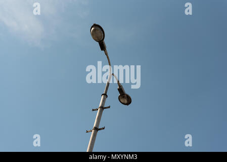 Alte industrielle street lamp gegen den blauen Himmel mit weißen Wolken. Stockfoto