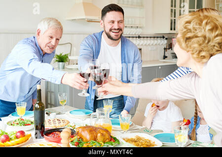 Portrait von glückliche zwei Generation Familie Abendessen zusammen anstoßen und ständigen Schiebeschalter an festlichen Tisch während der Ferien Feier Stockfoto