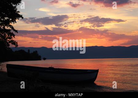 Farbenfroher Sonnenuntergang über dem Ohrid See mit Boot Silhouette Stockfoto