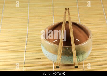 Japanische Teetasse mit bambusstöcken auf Pflanzenöl mat. Stockfoto