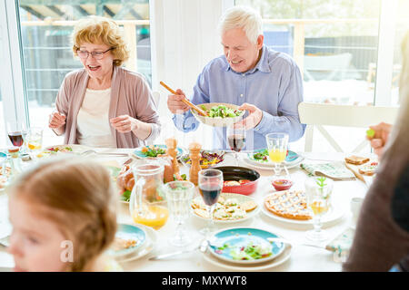 Portrait von Happy Family sie das Abendessen zusammen zu sitzen, die festlichen Tisch mit leckeren Gerichten, Focus zwei Großeltern, Kopie Raum Stockfoto