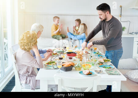 Portrait von Happy Family geniessen gemeinsam das Abendessen im Speisesaal mit festlichen Tisch in der modernen lichtdurchfluteten Wohnung sitzen, Platz kopieren Stockfoto