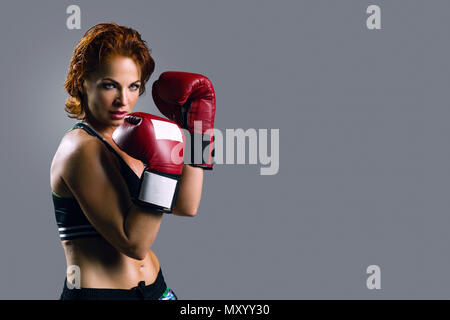 Portrait der Frau in Boxhandschuhen auf grauem Hintergrund. Stockfoto