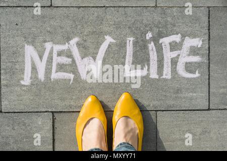 Weibliche Füße mit Text neues Leben auf Asphalt geschrieben. Stockfoto