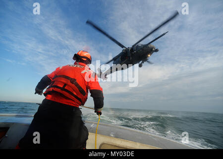 HAMPTON BAYS, NY-Flieger mit 101 Rescue Squadron und 103 Rescue Squadron Verhalten hoist Training mit United States Coastguardsmen von US Coast Guard Station Shinnecock zum 22. Dezember 2016. Während dieser Ausbildung, die Schutzengel aus der 103 RQS wurden über Hoist aus ein HH-60 Pavehawk auf das Deck des Schneidwerk abgesenkt. Danach wird das Flugzeug praktiziert Fallenlassen und Entfernen patient Würfe, vor dem Heben der Schutzengel sichern und für die Rückkehr zum Ausgangspunkt. (US Air National Guard/Staff Sergeant Christopher S. Muncy/freigegeben) Stockfoto