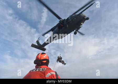 HAMPTON BAYS, NY-Flieger mit 101 Rescue Squadron und 103 Rescue Squadron Verhalten hoist Training mit United States Coastguardsmen von US Coast Guard Station Shinnecock zum 22. Dezember 2016. Während dieser Ausbildung, die Schutzengel aus der 103 RQS wurden über Hoist aus ein HH-60 Pavehawk auf das Deck des Schneidwerk abgesenkt. Danach wird das Flugzeug praktiziert Fallenlassen und Entfernen patient Würfe, vor dem Heben der Schutzengel sichern und für die Rückkehr zum Ausgangspunkt. (US Air National Guard/Staff Sergeant Christopher S. Muncy/freigegeben) Stockfoto