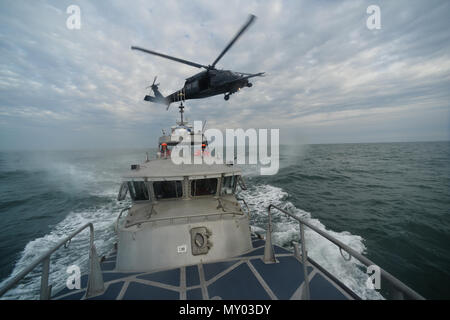 HAMPTON BAYS, NY-Flieger mit 101 Rescue Squadron und 103 Rescue Squadron Verhalten hoist Training mit United States Coastguardsmen von US Coast Guard Station Shinnecock zum 22. Dezember 2016. Während dieser Ausbildung, die Schutzengel aus der 103 RQS wurden über Hoist aus ein HH-60 Pavehawk auf das Deck des Schneidwerk abgesenkt. Danach wird das Flugzeug praktiziert Fallenlassen und Entfernen patient Würfe, vor dem Heben der Schutzengel sichern und für die Rückkehr zum Ausgangspunkt. (US Air National Guard/Staff Sergeant Christopher S. Muncy/freigegeben) Stockfoto