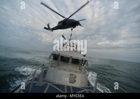 HAMPTON BAYS, NY-Flieger mit 101 Rescue Squadron und 103 Rescue Squadron Verhalten hoist Training mit United States Coastguardsmen von US Coast Guard Station Shinnecock zum 22. Dezember 2016. Während dieser Ausbildung, die Schutzengel aus der 103 RQS wurden über Hoist aus ein HH-60 Pavehawk auf das Deck des Schneidwerk abgesenkt. Danach wird das Flugzeug praktiziert Fallenlassen und Entfernen patient Würfe, vor dem Heben der Schutzengel sichern und für die Rückkehr zum Ausgangspunkt. (US Air National Guard/Staff Sergeant Christopher S. Muncy/freigegeben) Stockfoto