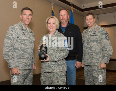 Oberst John Klein, 60 Air Mobility Wing Commander, (links) und Chief Master Sgt. Steve Nichols, (rechts) 60 AMC-Befehl Chief, Gegenwart Senior Master Sgt. Lisa Williams, 60. medizinische Gruppe, und ihr Ehemann, mit einer Flasche mit seiner Förderung Zeilennummer und Chief Master Sergeant Streifen als Familie, Freunde und Kollegen Travis Teammitglieder graviert zuhauf die neue US Air Force chief zu feiern wählt, im Delta Breeze Club, Travis Air Force, Calif., Dez. 8, 2016. Die Air Force gefördert 531 Senior Master Sgt's Chief Master Sgt., aus der 2.229, die für eine gesamte Auswahl Ratte Stockfoto