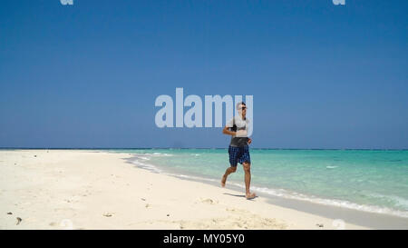 Mann laufen Strand entlang. Fitness Sport runner Mann Jogging am Strand. Hübscher junger fit Sportlich männlichen Athleten laufen außerhalb an einem wunderschönen Strand. Stockfoto