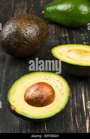 Die Avocado Hälften und Früchte auf hölzernen Hintergrundstreuung Stockfoto