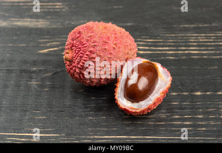 Reif lychee Obst in-shell die Hälfte auf der dunklen Tabelle Stockfoto