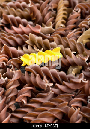 Vereinzelte dunkle rohe Pasta Fusilli mit einem gelben close-up Stockfoto