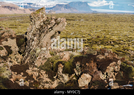 Moos Felsen outcroppings in der Eldrhaun Lavafelder von Island mit Bergen und Gletschern im Hintergrund Stockfoto
