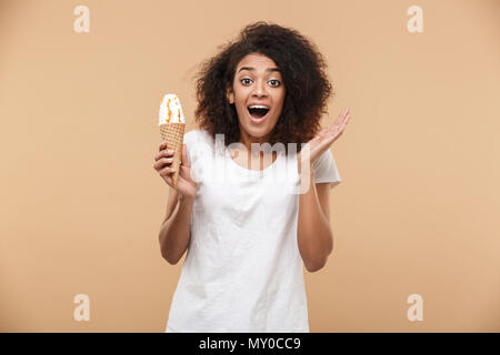 Portrait einer aufgeregt Junge afrikanische Frau mit Eis beige Hintergrund isoliert Stockfoto