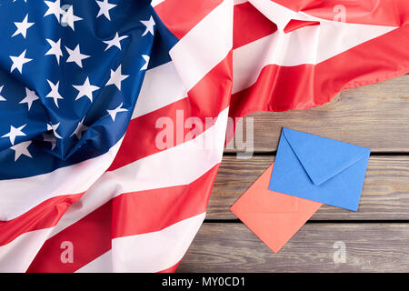 USA-Flagge, rote und blaue Umschläge. Zerknitterte amerikanische Flagge und bunte Briefumschläge auf Holz- Hintergrund. Stockfoto