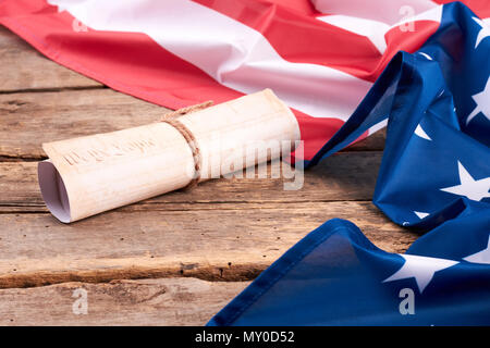 USA Verfassung rollte in Blättern. Patriotische Flagge der USA und der Erklärung der Unabhängigkeit der USA auf Holzplatten. Amerikanische Gesetze Konzept. Stockfoto