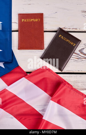 Pässe und USA-Flagge, Ansicht von oben. Amerikanischen patriotischen Fahne und zwei Pässen auf weißem Hintergrund Holz, Bild vertikal. Stockfoto