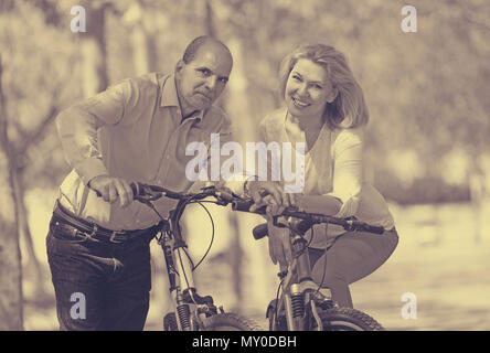 Lächelnd internationale Familie der aktiven Rentner mit Bikes im sonnigen Tag Stockfoto