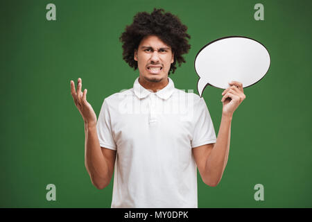 Bild von verwirrten jungen afrikanischen curly Mann über grüne Wand Hintergrund holding Sprechblase isoliert. Stockfoto