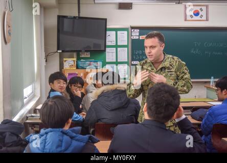 161221-N-SR 567-044 BUSAN, Republik Korea (31. 21, 2016) Petty Officer 1st Class Ty Connors, ein Seemann von Commander, U.S. Naval Forces Korea (CNFK), gratuliert ein Kursteilnehmer am Daecheon Middle School während eines freiwilligen Sitzung. Connors spendet seine Zeit Geschichten über das Leben in den USA teilen und jedes Kind Hilfe Englisch sprechen, indem Sie sich im Gespräch. CNFK ist Vertreter der U.S. Navy in der ROK, der Leitung und der Kompetenz in der Marine Fragen der institutionellen und operativen Wirksamkeit zwischen den beiden Marinen zu verbessern und der kollektiven Sicherheit Bemühungen in Korea zu stärken Stockfoto