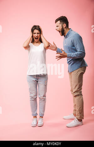 In voller Länge Porträt eines wütenden jungen Paar in ein Argument über rosa Hintergrund isoliert Stockfoto