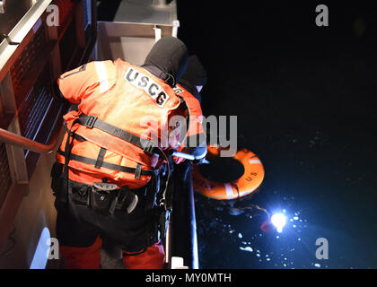 NEW YORK - zwei Besatzungsmitglieder von der Coast Guard Station Montauk ein Bootshaken mit einem Rettungsring und Positionsleuchte über Bord während der Nacht Bohrer in Long Island Sound am 13. Dezember 2016 geworfen wurden, zu erreichen. Stationen benötigt Bohrer in der Nacht durchgeführt werden, um für jede Situation zu jeder Stunde des Tages vorzubereiten. (U.S. Coast Guard Foto von Petty Officer 3rd Class Steve Strohmaier) Stockfoto